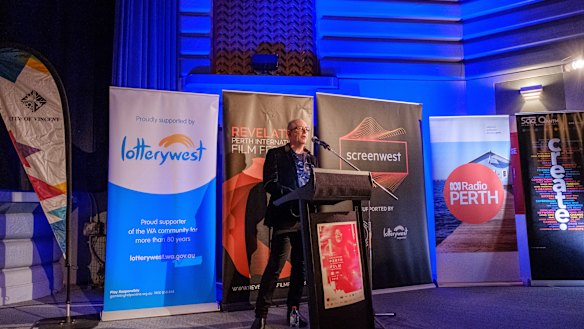 Richard Sowada speaks before signage from principal festival sponsors. 