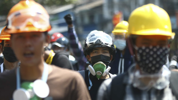 Anti-coup protesters wearing helmets and masks take positions as police gather in Yangon, Myanmar, on Friday.