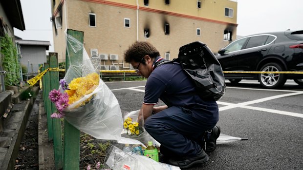 A man places flowers outside the destroyed studio.