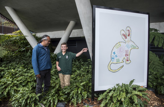 Artist Liam, aged 11, with his bilby artwork being shown to older artist, Neil Thorne.