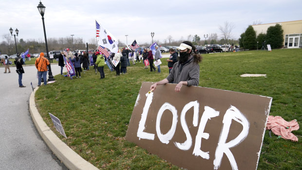 Supporters of President Donald Trump, left, gather as a counter protester holds a sign outside of the Wyndham Hotel where the Pennsylvania State Senate Majority Policy Committee met during the week.