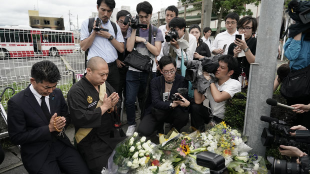 Japanese Diet member, Kenta Izumi, left, and Buddhist monk, Matsumoto Genkun, pay respects at a makeshift memorial outside the Kyoto Animation studio.