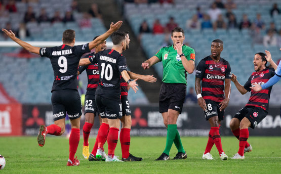 Appealing: Referee Shaun Evans is swamped by Wanderers players during Saturday night's Sydney derby.