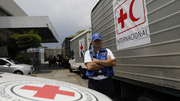 A convoy of trucks arrive at a warehouse to transport the first shipment of aid.