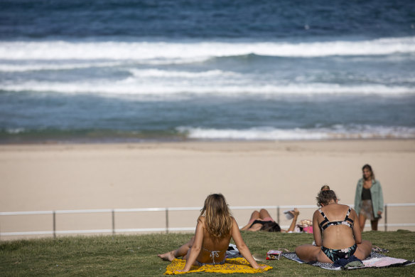 People sit beside a closed Bondi Beach on Friday afternoon.