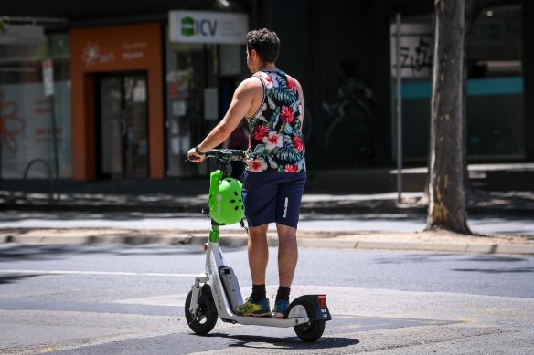 A Lime e-scooter rider in the CBD travels without wearing the available helmet.