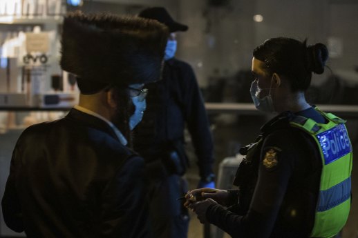 Members of Victoria Police take down the details of people outside the illegal gathering.