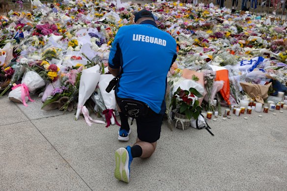 A lifeguard places flowers at the  memorial for the mass-shooting victims at the Bondi Pavilion.