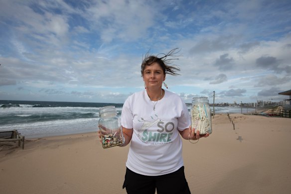 Sarah-Jo Lobwein from Sutherland-based environment group SO Shire holds up two jars of waste collected from Wanda Beach, Cronulla.