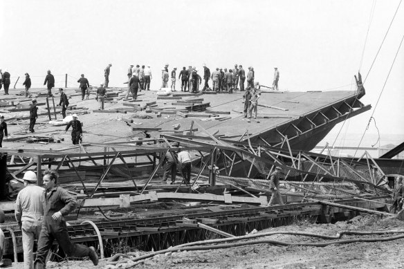 Workers stand on the fallen span of the West Gate Bridge after its collapse.