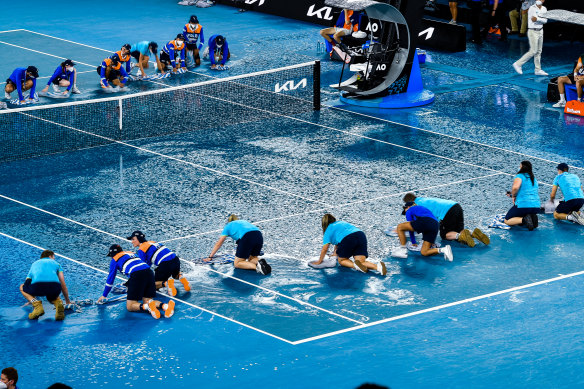 Ball kids dry the centre court after sudden rain at the Australian Open on Wednesday.