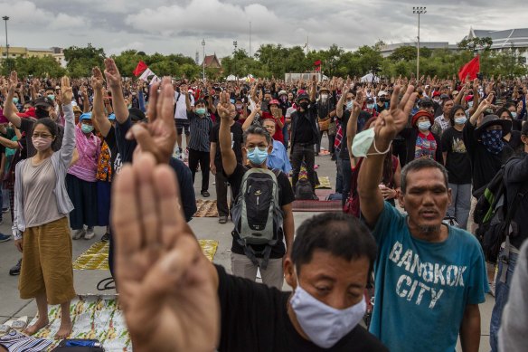Anti-government protestors hold up a three finger salute during a rally at Sanam Luang on Sunday. 
