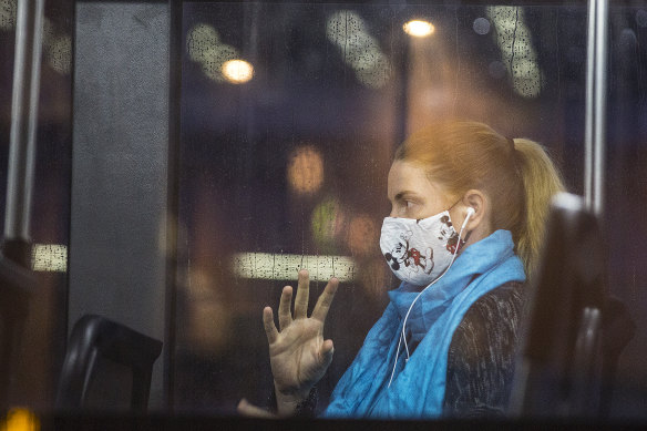 A woman wears a mask on a bus at Parramatta to protect against the spread of COVID-19.
