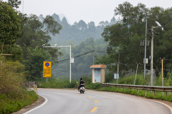 A young man rides by the barbed-wire fences and surveillance cameras along China-Vietnam border in Detian Village