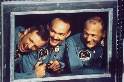 Apollo 11 astronauts (L-R) Aldrin, Collins and Armstrong peering out the window of a quarantine room aboard recovery ship Hornet following splashdown.