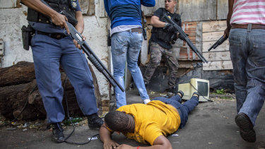 A man lays on the ground after being arrested in Jeppe's Town, Johannesburg on Tuesday. 