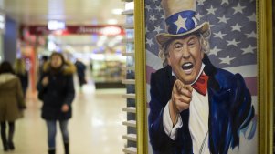 People walk past a caricature picture of US President Donald Trump on sale in a shopping mall in Moscow.