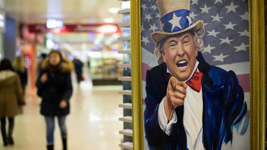 People walk past a caricature picture of US President Donald Trump on sale in a shopping mall in Moscow.