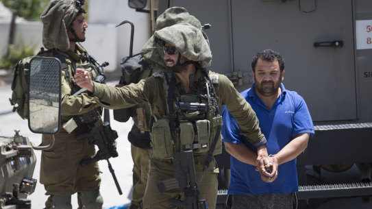 Israeli soldiers make one of several arrests of Palestinians last month after a soldier of their occupation force was killed by a rock thrown from a rooftop in the West Bank village of Yabad. 