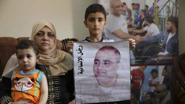 Amro el Halabi holds a picture of his father, Mohammed, who was the Gaza director of the international charity World Vision, now found guilty of diverting sums to Hamas that exceed its total budget,