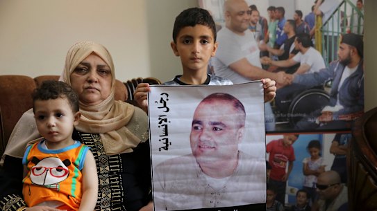 Amro el Halabio, 7, holds a picture of his father, Mohammed, who was the Gaza director of the international charity World Vision, now found guilty of diverting sums to Hamas that exceed its total budget,