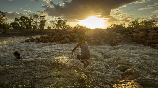A girl jumps into the water at Brewarrina Weir, which overflowed for the first time in years after February's rain.