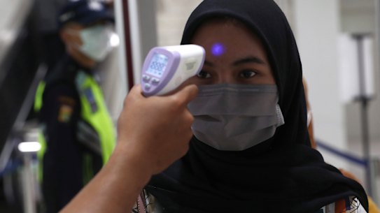 A medical team checks passenger body temperature at an underground station in Jakarta.