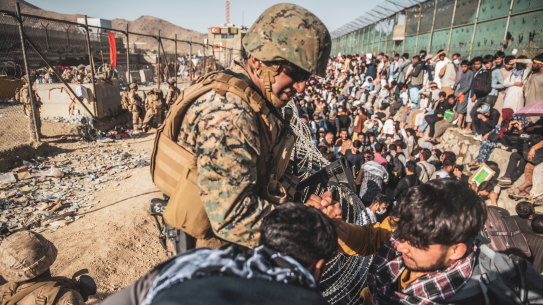 A U.S. Marine assists at an Evacuation Control Check Point (ECC) during an evacuation at Hamid Karzai International Airport in Kabul, Afghanistan.