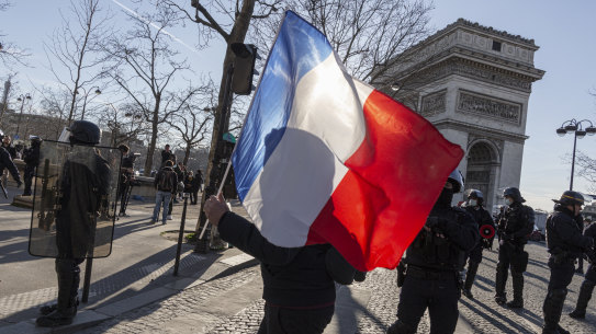  A “Freedom Convoy” supporter carries a French flag at the Arc de Triomphe, in France, where restrictions have been dropped.