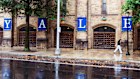 A woman walks by a Yale sign reflected in the rainwater on the Yale University campus.
