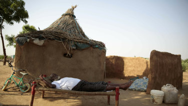 A man rests on a bed in front of his hut at a camp for internally displaced people near the town of Abs, Yemen. 