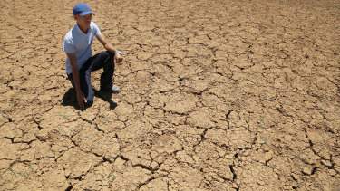 Farmer Paul van Wyk kneels down in a cracked bed of a water pan in Vosburg, South Africa. The worst drought in decades is affecting much of southern Africa.