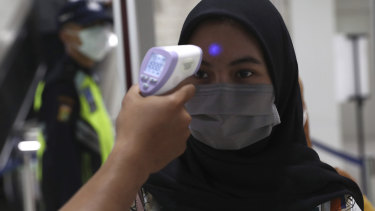 A medical team checks passenger body temperature at an underground station in Jakarta.