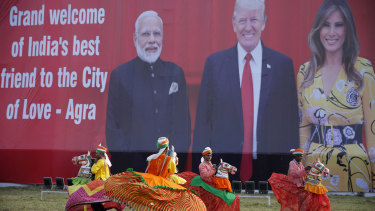 Indian folk dancers rehearse their performance next to a billboard featuring Indian Prime Minister Narendra Modi, US President Donald Trump and first lady Melania Trump at the airport in Agra, India.