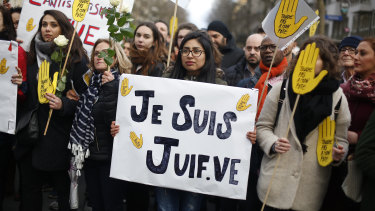 A woman carries a poster reading "I am a jew" as she attends a silent march to honour an 85-year-old woman who escaped the Nazis 76 years ago but was stabbed to death in her Paris apartment in March, apparently because she was Jewish.