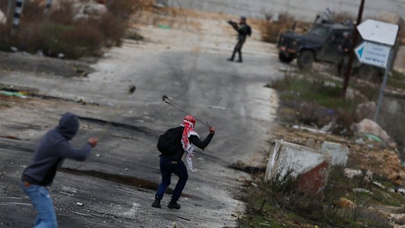 Palestinian demonstrators throw stones during clashes with Israeli security forces as they protest the Trump Middle East peace plan at Beit El checkpoint, near the West Bank city of Ramallah.