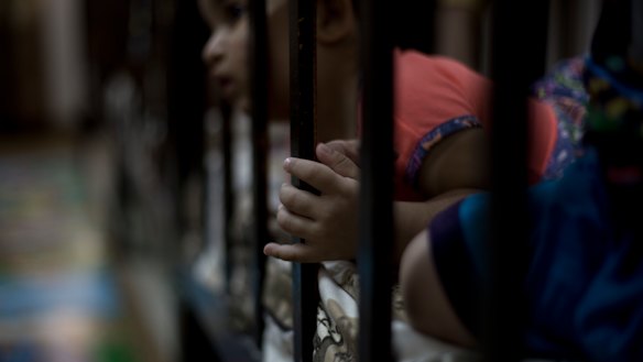 A child peeks out from her crib at Salhiya Orphanage.