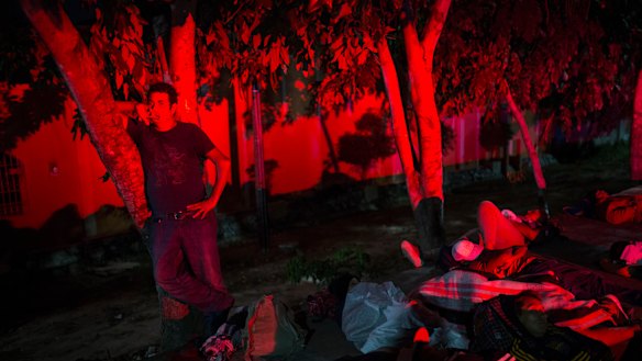 A man stands among other migrants while waiting for a ride on the side of the road, as a caravan of Central Americans continues its slow march towards the US border near Tapanatepec, Mexico.