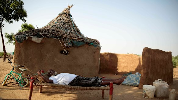 A man rests on a bed in front of his hut at a camp for internally displaced people near the town of Abs, Yemen. 