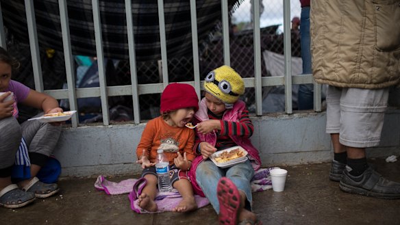 Merary Alejandra feeds her three-year-old sister Britany Sofia, outside a migrant shelter in Tijuana on Thursday.