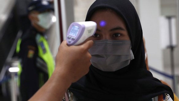A medical team checks passenger body temperature at an underground station in Jakarta.