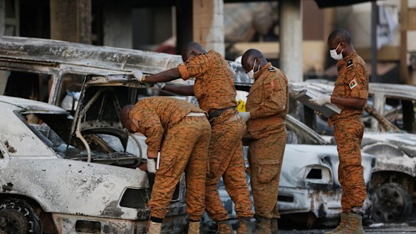 Soldiers examine burnt-out cars outside the Splendid Hotel in Ouagadougou, Burkina Faso, in 2016.