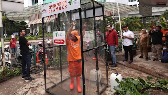 A government worker stands inside a makeshift sterilisation chamber in hopes of reducing the spread of the coronavirus in Jakarta.