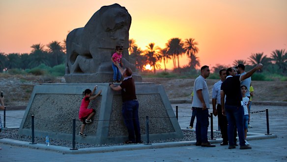 People stand near the Lion of Babylon at the archaeological site of Babylon, Iraq, on Friday.