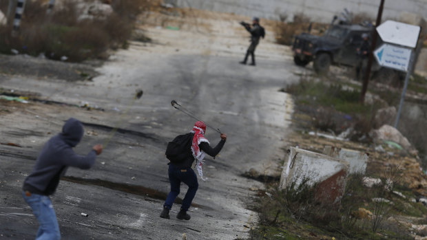 Palestinian demonstrators throw stones during clashes with Israeli security forces as they protest the Trump Middle East peace plan at Beit El checkpoint, near the West Bank city of Ramallah.