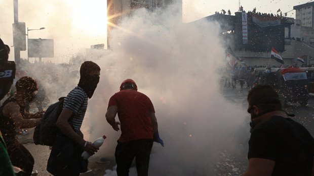 Anti-government protesters run to take cover while Iraqi Security forces fire tear gas during a demonstration in Tahrir Square in Baghdad, Iraq.
