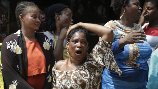 A woman cries as the body of a child is recovered from the rubble of a collapsed building in Lagos, Nigeria.