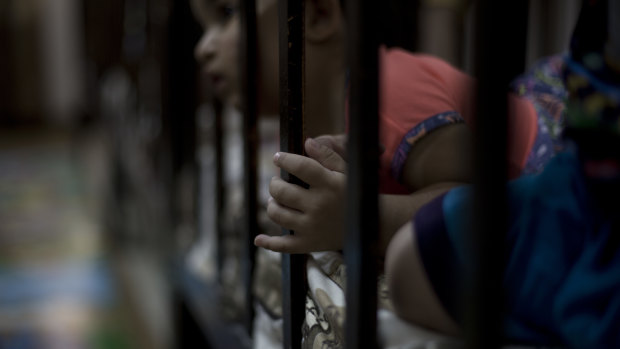 A child peeks out from her crib at Salhiya Orphanage.