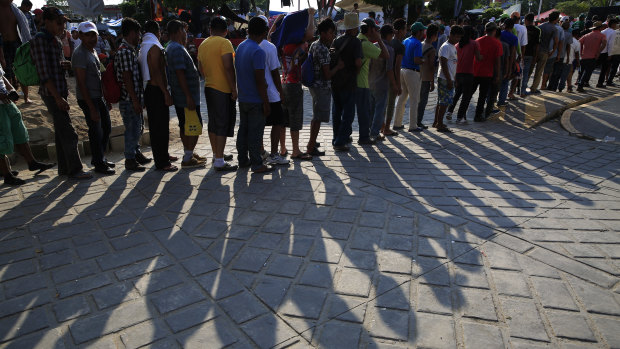 Migrant men wait in line to receive food handouts, in Tapanatepec, Mexico.