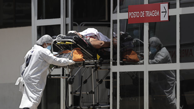 Health workers push a patient suspected of having COVID-19 into the HRAN Hospital in Brasilia, Brazil, on Thursday.